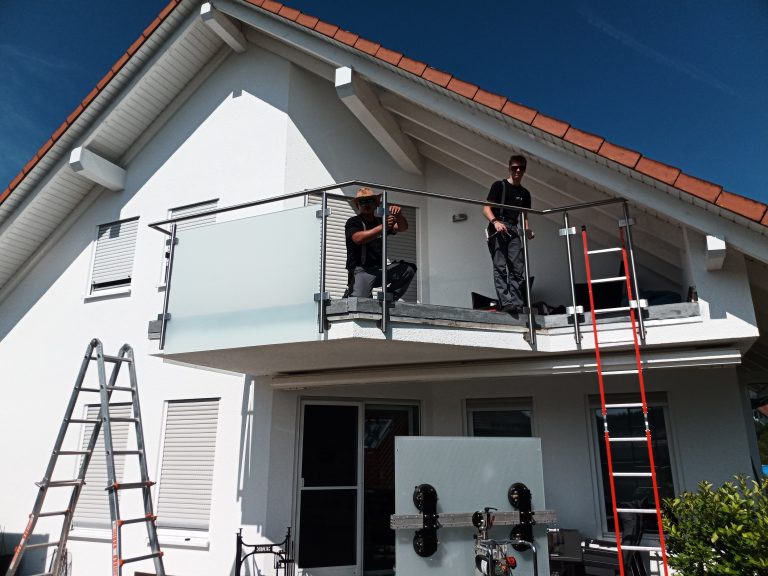 Mitarbeiter montieren Glasscheiben bei Balkongeländer
